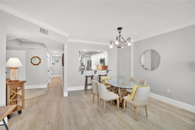 dining room featuring ornamental molding, light hardwood / wood-style flooring, and an inviting chandelier