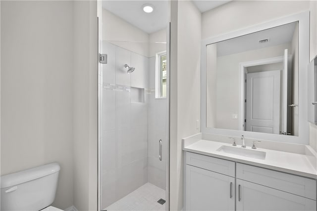 bathroom featuring a shower with shower door, vanity, and toilet