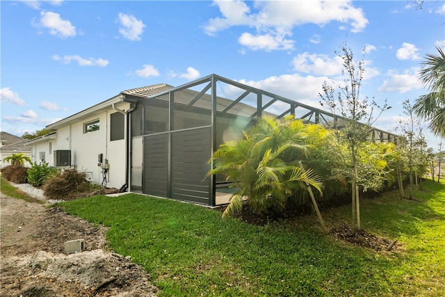 view of side of property featuring a lanai, cooling unit, and a yard