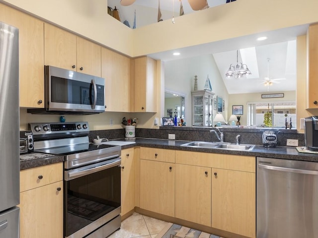 497 7th St, Vero Beach, FL 32962 - kitchen with stainless steel appliances, light brown cabinets, a sink, and high vaulted ceiling