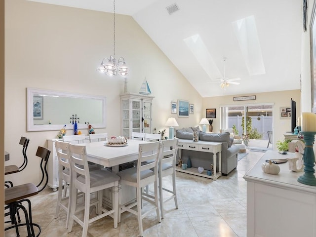 dining space featuring a skylight, high vaulted ceiling, and a chandelier