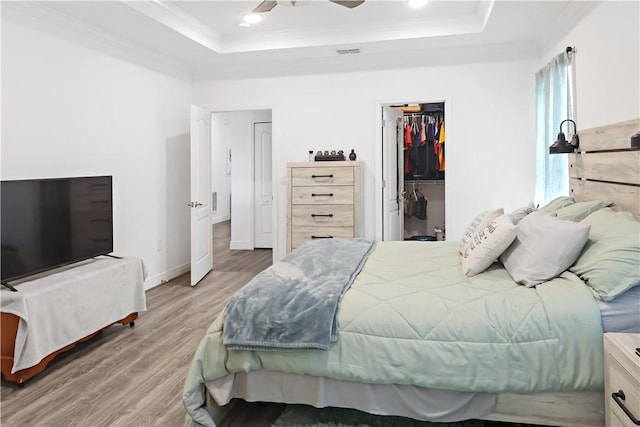 4308 Lago Vista Dr, Sebastian, FL 32976 - bedroom with a tray ceiling, crown molding, light wood-style floors, a spacious closet, and ceiling fan