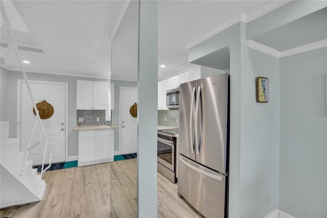 kitchen with white cabinets, ornamental molding, stainless steel appliances, and tasteful backsplash