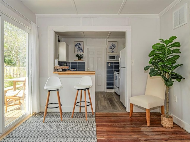 2047 38th Ave, Vero Beach, FL 32960 - kitchen featuring white appliances, wood finished floors, a breakfast bar, wooden counters, and a peninsula