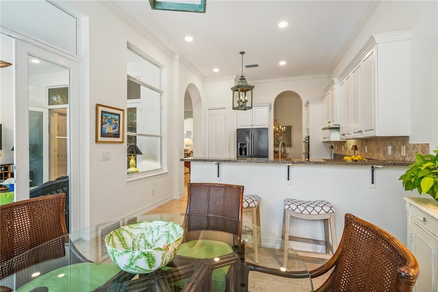 kitchen with pendant lighting, white cabinetry, kitchen peninsula, black fridge with ice dispenser, and dark stone counters