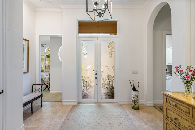 foyer featuring light tile patterned floors, crown molding, french doors, and a chandelier