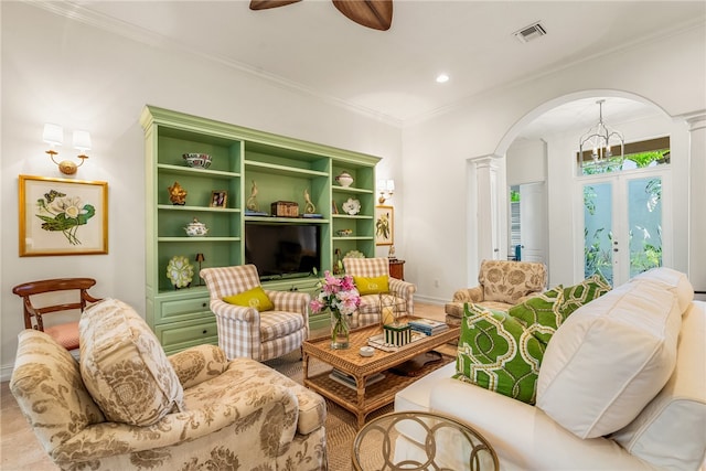 living room featuring decorative columns, ornamental molding, ceiling fan with notable chandelier, and french doors