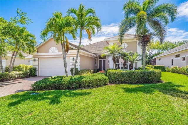 1217 Riverwind Cir, Vero Beach, FL 32967 - mediterranean / spanish home featuring stucco siding, a garage, a front lawn, driveway, and a tiled roof