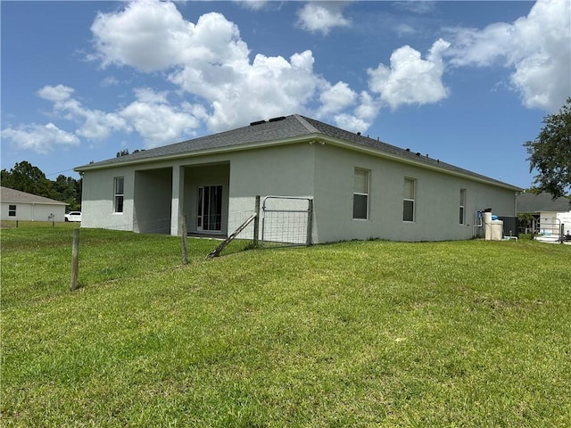 8475 101st Ct, Vero Beach, FL 32967 - rear view of property with stucco siding, a lawn, and a shingled roof