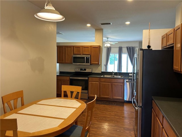 8475 101st Ct, Vero Beach, FL 32967 - kitchen with appliances with stainless steel finishes, dark wood finished floors, brown cabinets, dark countertops, and recessed lighting