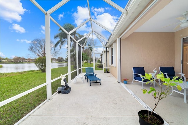 view of patio with a lanai, ceiling fan, and a water view