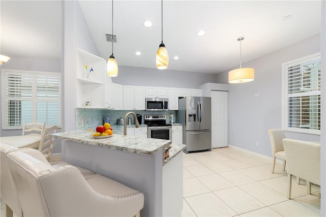 kitchen featuring pendant lighting, appliances with stainless steel finishes, white cabinetry, tasteful backsplash, and kitchen peninsula