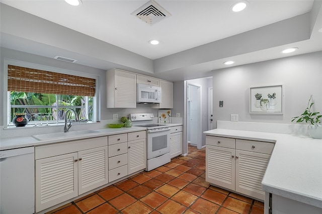 kitchen featuring dark tile patterned floors, white appliances, and sink