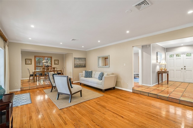 living room featuring crown molding, a wealth of natural light, and light hardwood / wood-style flooring