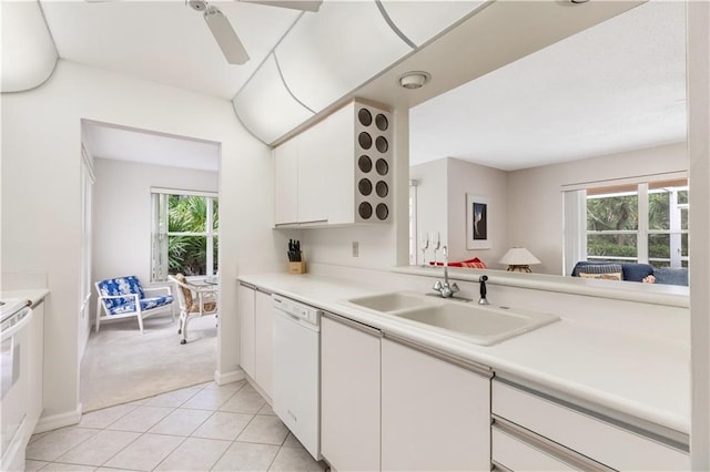 kitchen with white dishwasher, white cabinetry, light carpet, and a wealth of natural light