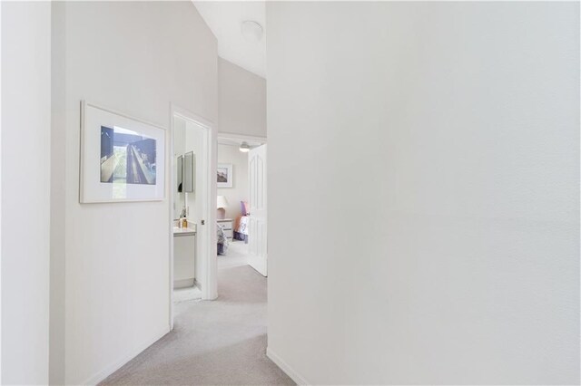 hallway featuring light carpet and high vaulted ceiling