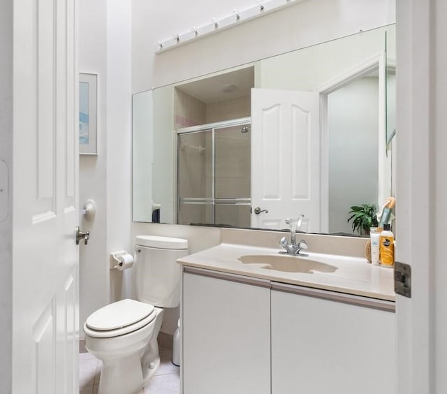 bathroom featuring tile patterned flooring, vanity, toilet, and walk in shower