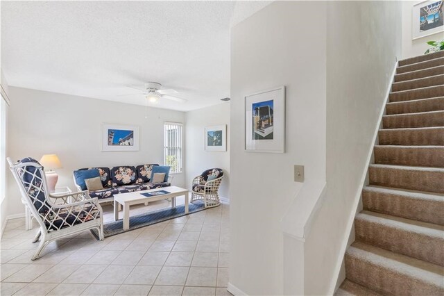 living room with ceiling fan, light tile patterned floors, and a textured ceiling