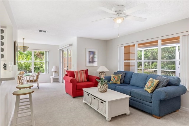 living room featuring light carpet, ceiling fan, and a textured ceiling