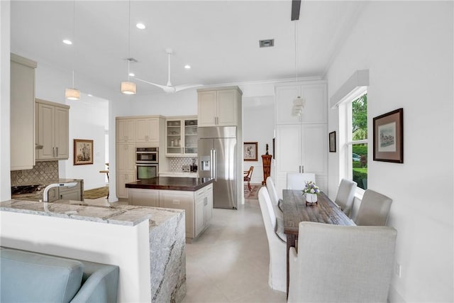 1242 River Reach Dr, Vero Beach, FL 32967 - kitchen featuring appliances with stainless steel finishes, cream cabinetry, tasteful backsplash, a center island, and recessed lighting