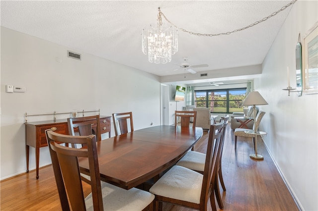 dining space with wood finished floors, visible vents, and baseboards