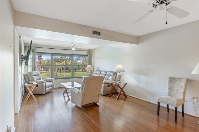 living area with baseboards, visible vents, ceiling fan, and hardwood / wood-style floors