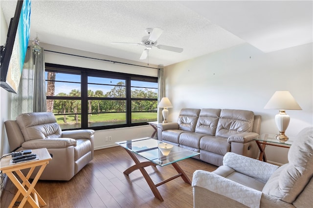 living area with ceiling fan, a textured ceiling, and wood finished floors