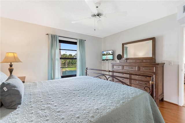 bedroom with a textured ceiling, visible vents, wood finished floors, and a ceiling fan