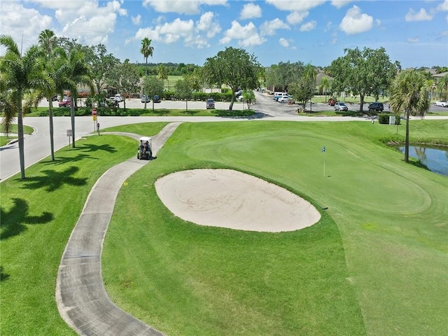 view of property's community featuring view of golf course and a yard