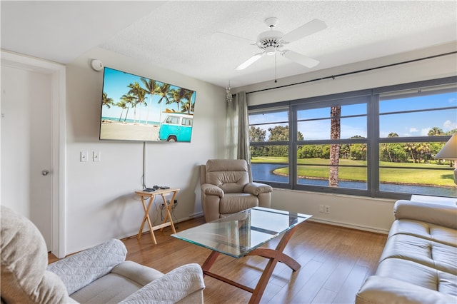 living room with a ceiling fan, a textured ceiling, and wood finished floors