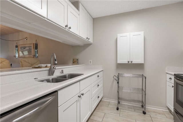 kitchen with light countertops, appliances with stainless steel finishes, a sink, and white cabinets