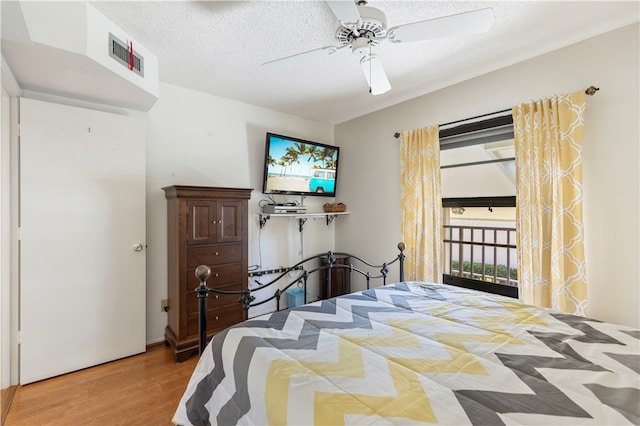 bedroom with access to exterior, visible vents, a ceiling fan, a textured ceiling, and wood finished floors