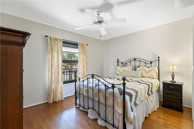 bedroom with a textured ceiling, ceiling fan, wood finished floors, and baseboards