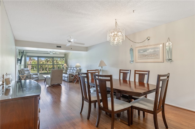 dining room with dark wood-style flooring, visible vents, a textured ceiling, and ceiling fan with notable chandelier