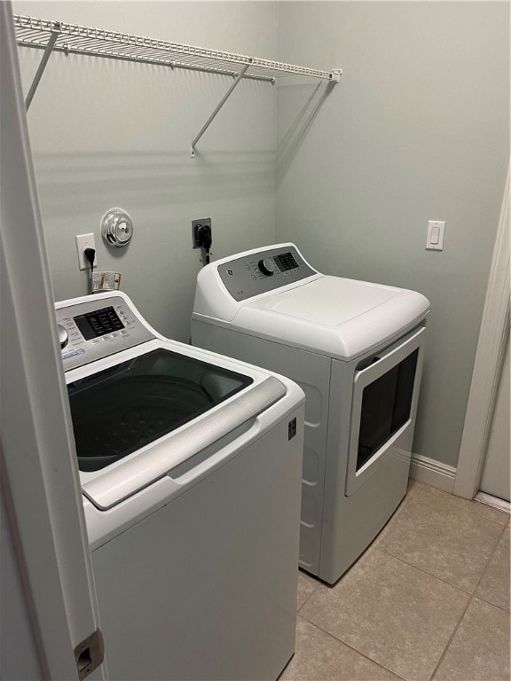 clothes washing area featuring light tile patterned flooring and separate washer and dryer