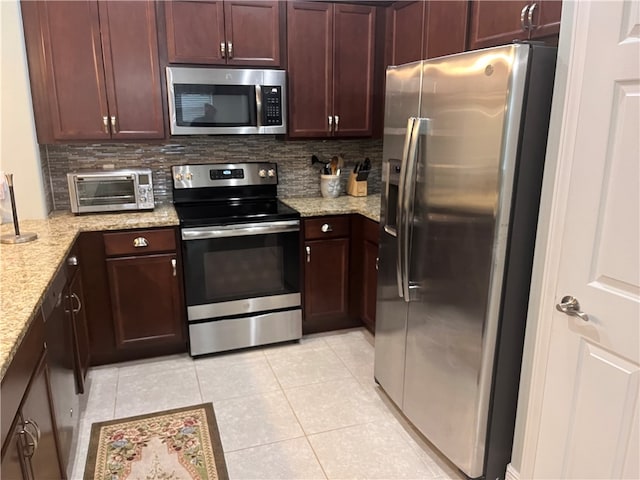 kitchen with light tile patterned flooring, light stone counters, appliances with stainless steel finishes, and tasteful backsplash