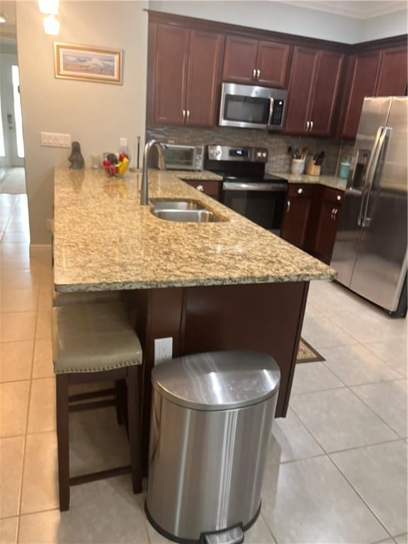 kitchen with sink, stainless steel appliances, a kitchen breakfast bar, backsplash, and kitchen peninsula