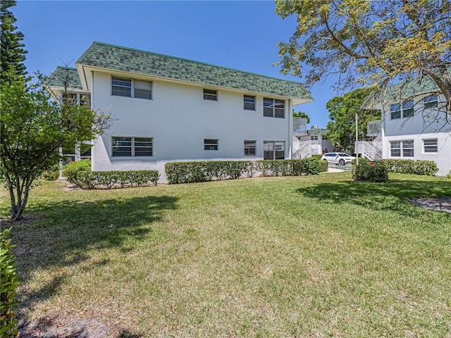 2800 Indian River Blvd Unit 10R, Vero Beach, FL 32960 - back of house featuring a shingled roof, stucco siding, and a yard