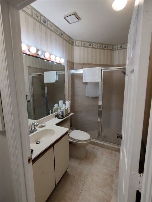 bathroom featuring toilet, tile patterned flooring, vanity, and walk in shower