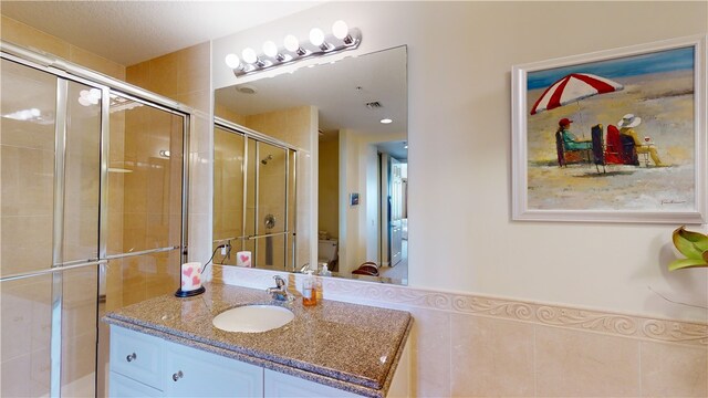 bathroom featuring vanity, toilet, and a shower with shower door