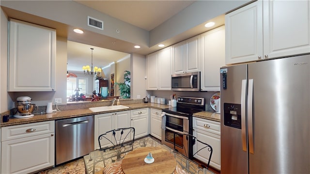 kitchen featuring white cabinetry, appliances with stainless steel finishes, sink, and a notable chandelier