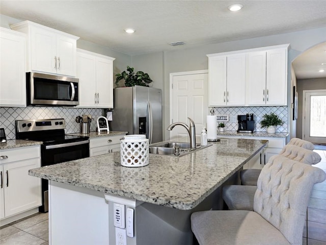 kitchen with sink, white cabinetry, stainless steel appliances, and an island with sink