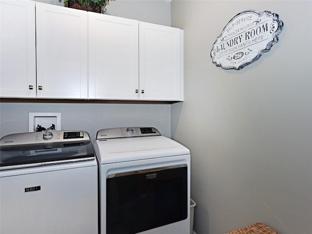 washroom with washer and dryer and cabinets