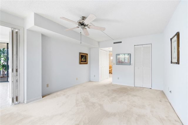 unfurnished room with a textured ceiling, light colored carpet, and ceiling fan