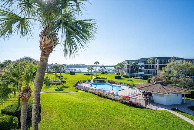 view of pool with a water view and a lawn