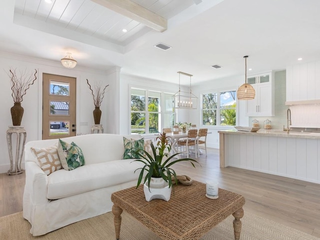 living room featuring beam ceiling, sink, and light hardwood / wood-style floors