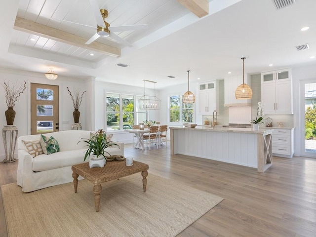 living room with ceiling fan, light hardwood / wood-style floors, and beamed ceiling