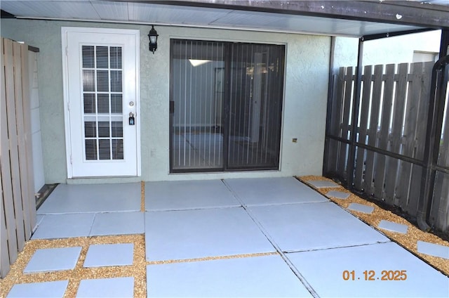 view of exterior entry with a patio area