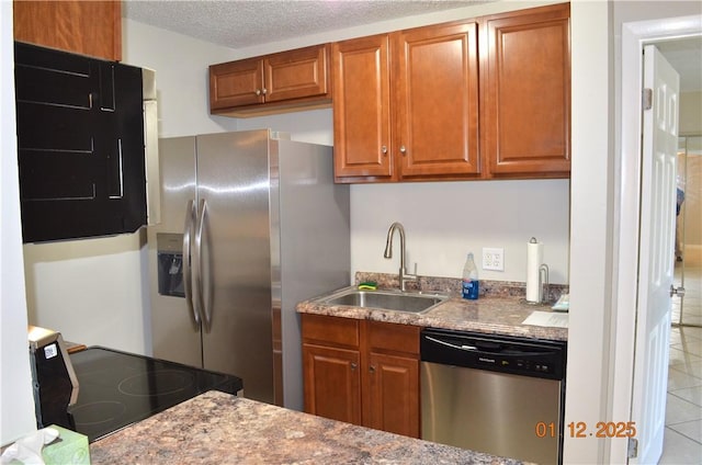 kitchen with stainless steel appliances, light stone countertops, sink, and a textured ceiling