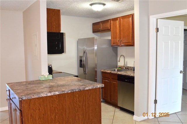 kitchen featuring sink, light tile patterned flooring, a textured ceiling, and appliances with stainless steel finishes